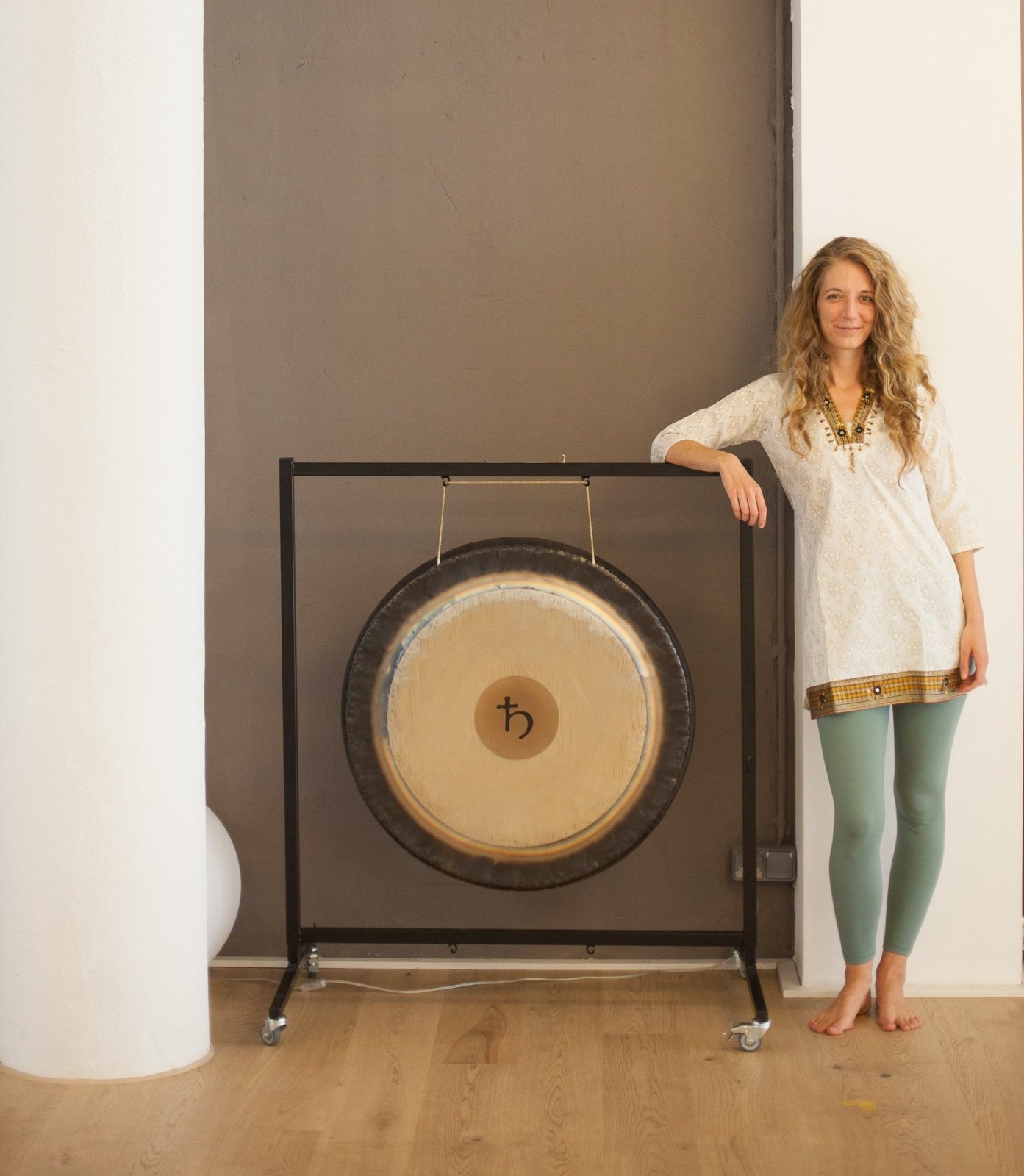 Leda Fay standing beside a large gong on its stand