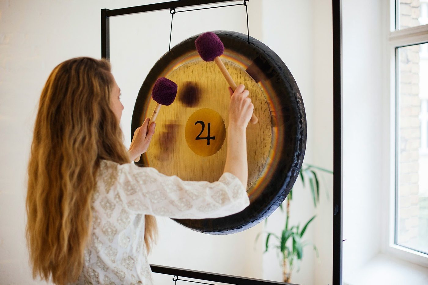 Leda Fay playing a large gong with two mallets